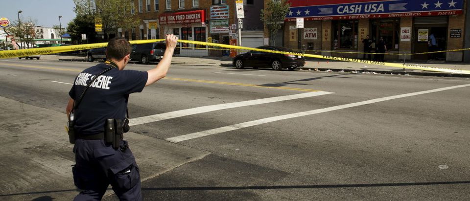 A police crime scene technician heads in to document evidence at the scene of a shooting at the intersection of West North Avenue and Druid Hill Avenue in West Baltimore, Maryland May 30, 2015. REUTERS/Jim Bourg
