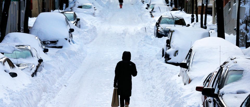 A pedestrian walks in the middle of the street following a winter blizzard in Boston