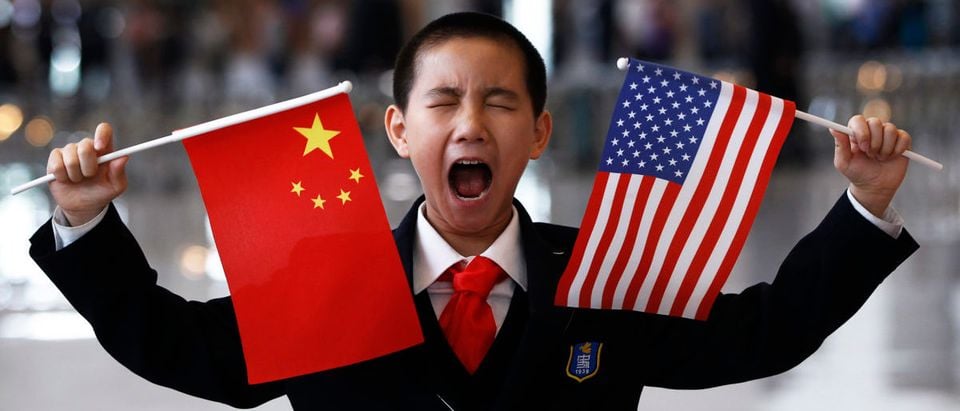 A boy who is waiting to greet U.S. Secretary of State Clinton at the National Museum makes a face while holding the U.S. and Chinese flags in Beijing