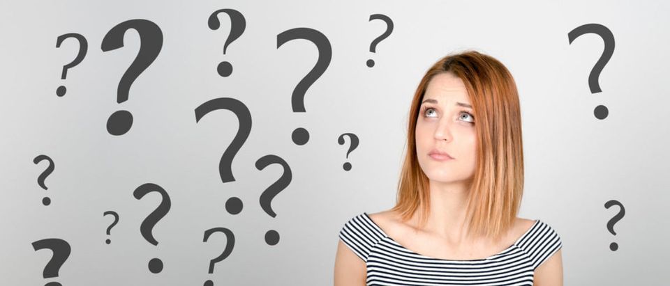 A woman is confused why there are question marks suspended in the air around her. (Shutterstock/Peppinuzzo)