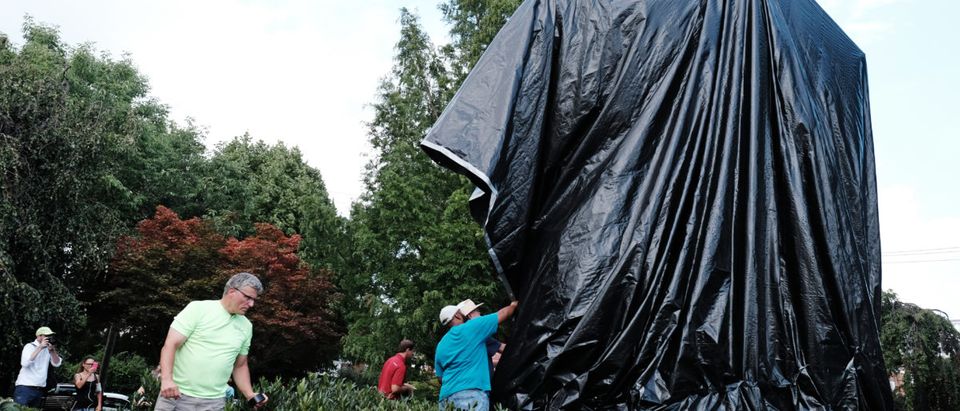 Workers replace the black tarp with which the City of Charlottesville covered the statue of Confederate General Robert E. Lee after John Miska (not shown) attempted to remove the covering in Charlottesville, Virginia, U.S., August 23, 2017. REUTERS/Justin Ide
