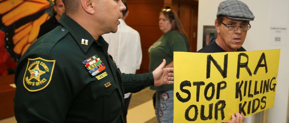 A man with a sign is seen after the news conference in the hallway outside the courtroom where Nikolas Cruz appeared via video at a bond court hearing after being charged with 17 counts of premeditated murder, in Fort Lauderdale, Florida, U.S., February 15, 2018. REUTERS/Charles Trainor, jr./Pool