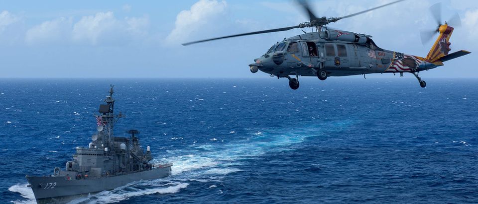 A U.S. MH-60S Sea Hawk flies by Japan's Maritime Self-Defense Force ship JS Shimakaze above waters around Okinawa southwest of the Korean peninsula