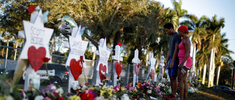 Adin Chistian, student of the Marjory Stoneman Douglas High School and his mother Denyse, look at the crosses and Stars of David placed in front of the fence of the school to commemorate the victims of the mass shooting, in Parkland