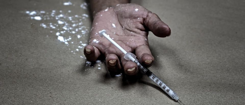 Drug abuse concept., overdose asian female drug addict hand, drugs narcotic syringe in hand on the floor. (SanchaiRat/Shutterstock)