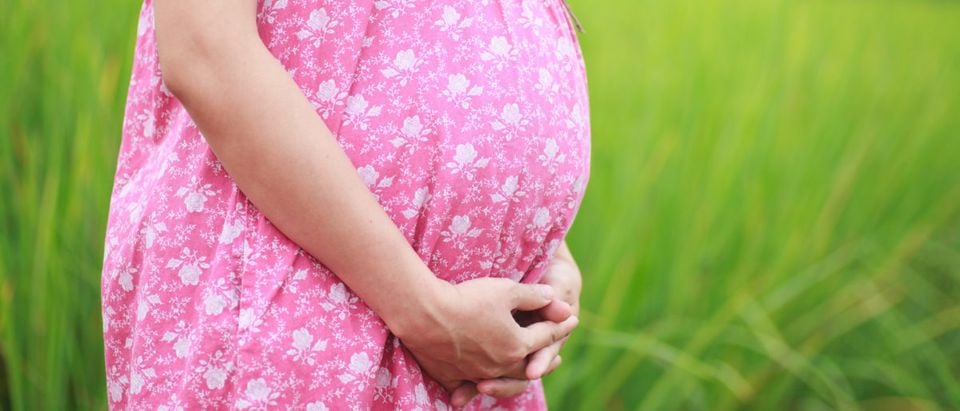 A pregnant teen is holding her belly. (Shutterstock/Thanatip S)