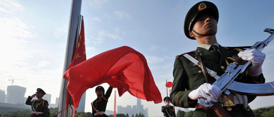 A paramilitary policeman unfurls a Chinese national flag during a flag-raising ceremony to mark the 65th anniversary of the founding of the People's Republic of China, in Hefei
