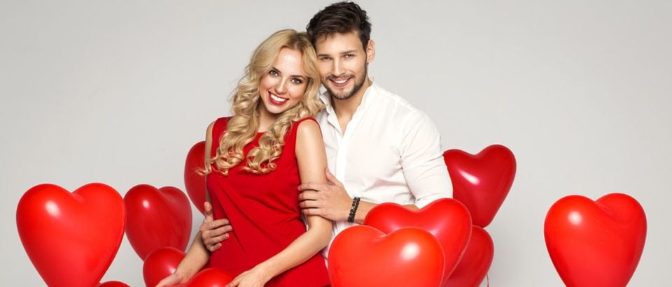 A young, loving couple poses with heart balloons on Valentine's Day. (Shutterstock/kiuikson)