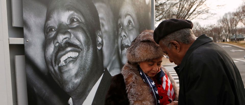In front of a photo of Dr. Martin Luther King Jr. and Coretta Scott King, James and Jewelle Gibbs of Oakland, CA, find their IDs for entry to the ground breaking ceremony for the Smithsonian National Museum of African American History and Culture on the National Mall in Washington February 22, 2012. REUTERS/Kevin Lamarque