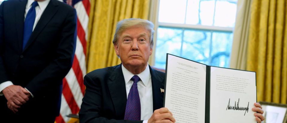 FILE PHOTO: U.S. President Donald Trump, flanked by U.S. Trade Representative Robert Lighthizer, holds up a directive to impose tariffs on imported washing machines after signing it in the Oval Office at the White House in Washington, U.S. January 23, 2018. REUTERS/Jonathan Ernst/File Photo