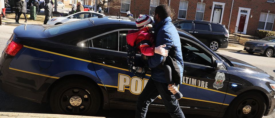 A man stops to thank the police as activists, residents and those that have lost a loved one to violence participate in a "Peace and Healing Walk" in an area with a high rate of homicides during Baltimore's third "Ceasefire Weekend" on February 3, 2018 in Baltimore, Maryland. The walk stopped at numerous locations where an individual was recently murdered to say a prayer. Baltimore, one of the poorest major cities in the United States, experienced 341 homicides last year, the highest per-capita rate on record for the city. The third citywide Ceasefire event began on Friday, with organizers and community members calling for peace for a 72-hour period and holding numerous events, including peace walks, movie screenings and a youth basketball tournament among other gatherings. (Photo by Spencer Platt/Getty Images)