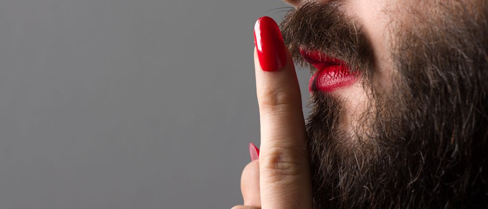 Bearded Man with Red Lipstick on His Lips and Nail Polish Making Silence Gesture