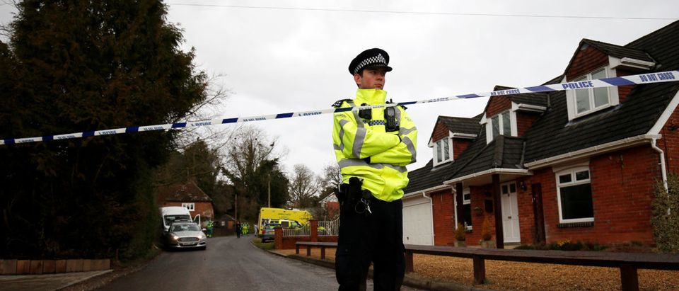 A police officer stands at a cordon as soldiers wearing protective suits and members of the emergency services work at a site in Winterslow, near Salisbury