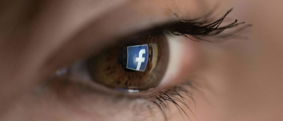 An illustration picture taken on March 22, 2018 in Paris shows a close-up of the Facebook logo in the eye of an AFP staff member posing while she looks at a flipped logo of Facebook. (Photo: CHRISTOPHE SIMON/AFP/Getty Images)