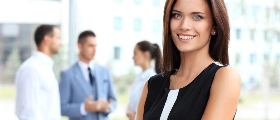 Face of beautiful woman on the background of business people Shutterstock/ OPOLJA