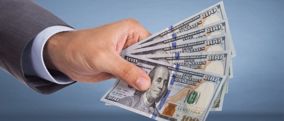 A man doles out money. (Shutterstock/Andrey_Popov) | Teachers Spend $500 For School Supplies