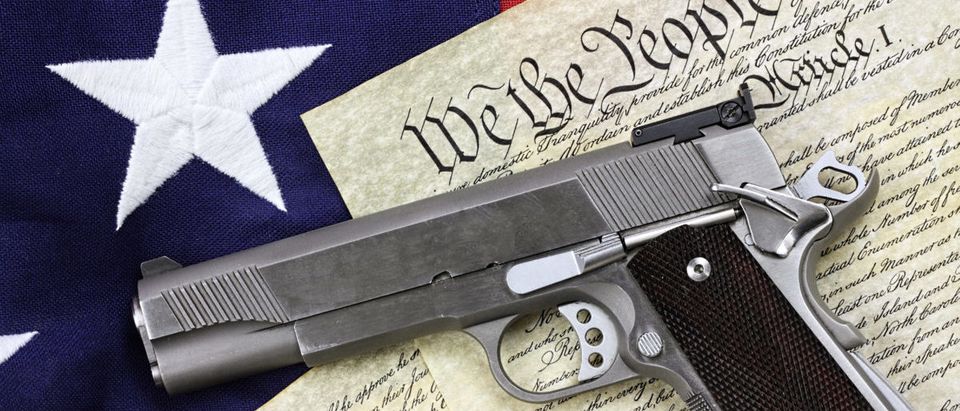 Handgun lying over a copy of the United States constitution and the American flag - ShutterStock Stephanie Frey | Teacher Made Kids Write Anti-Gun Letters | CBS Fails In Finding Outrage Over Photo