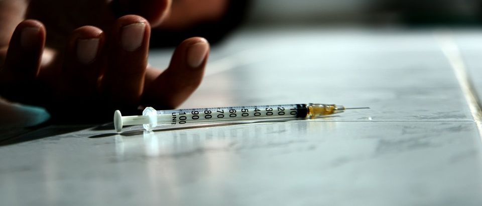 Syringe with heroin in front of drug addict male. (C_KAWI/Shutterstock)