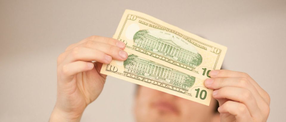 A man examines two ten-dollar bills. (Shutterstock/Blue_Deep)