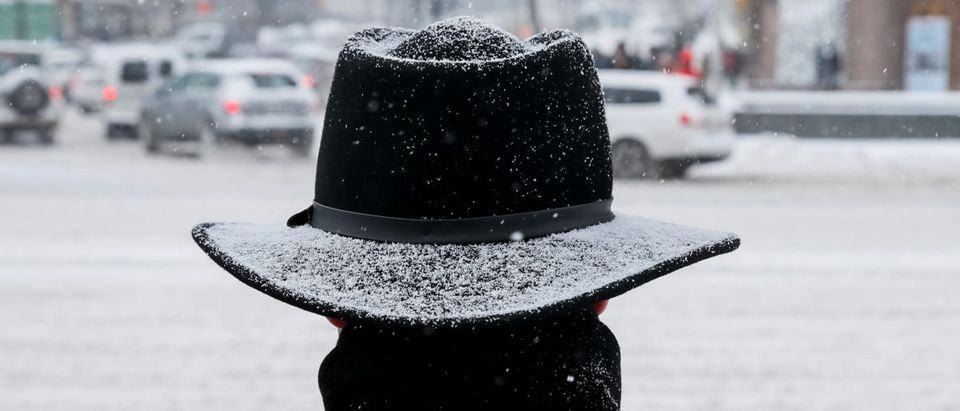 A man waits before crossing a street amid a snow flurry in central Kiev