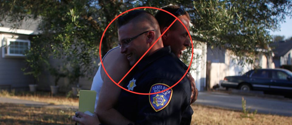 Calvin Sanders hugs Santa Rosa police officer Travis Dunn while receiving a pass that allows him to come and go from the evacuation zone he lives in after a wildfire tore through adjacent streets in Santa Rosa, California, U.S. October 15, 2017. REUTERS/Jim Urquhart
