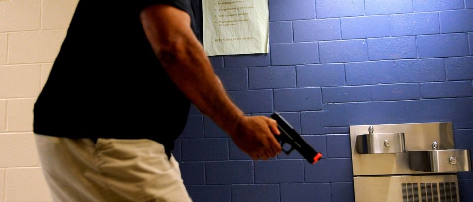 A school resource officer makes his way down a hallway with his training pistol in-hand as he attempts to locate an armed subject while taking part in an "active shooter" training exercise at Freedom Middle School, during the annual National Association of School Resource Officers conference in Orlando, Florida July 18, 2013. REUTERS/Brian Blanco
