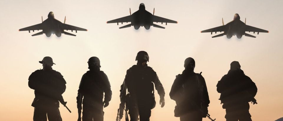 Soldiers stand with aircrafts above them. (Shutterstock/BPTU)