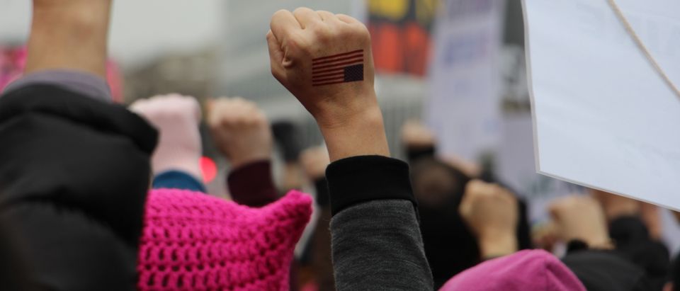 Woman's fist with US flag raised in the air at Women's March in Washington DC. (Shutterstock)