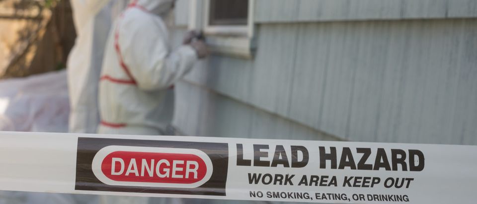 Two house painters in hazmat suits remove lead paint from an old house. (Shutterstock/Jamie Hooper)