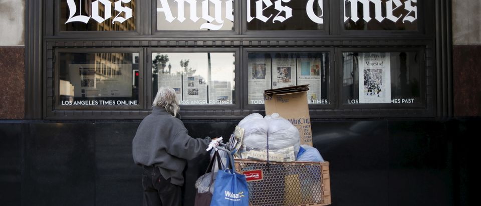 A homeless man reads the Los Angeles Times in the window of the building of Los Angeles Times newspaper, which is owned by Tribune Publishing Co, in Los Angeles