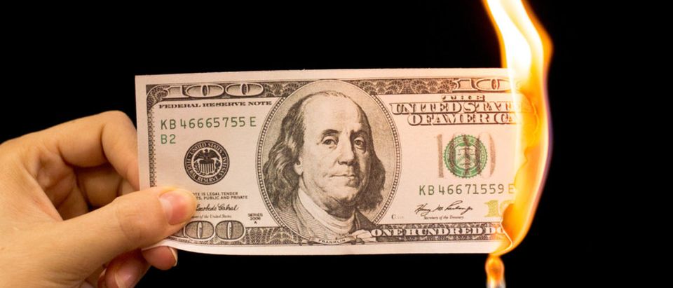 Someone sets fire to a hundred-dollar bill. (Shutterstock/schankz)