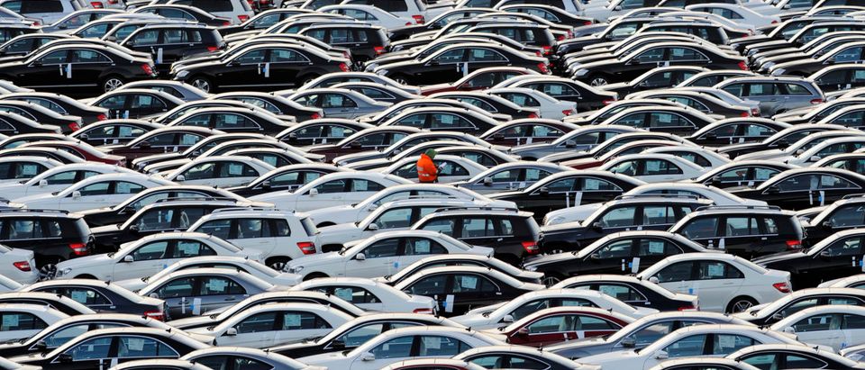A worker walks along rolls of Mercedes cars at a shipping terminal in the harbor of the German northern town of Bremerhaven