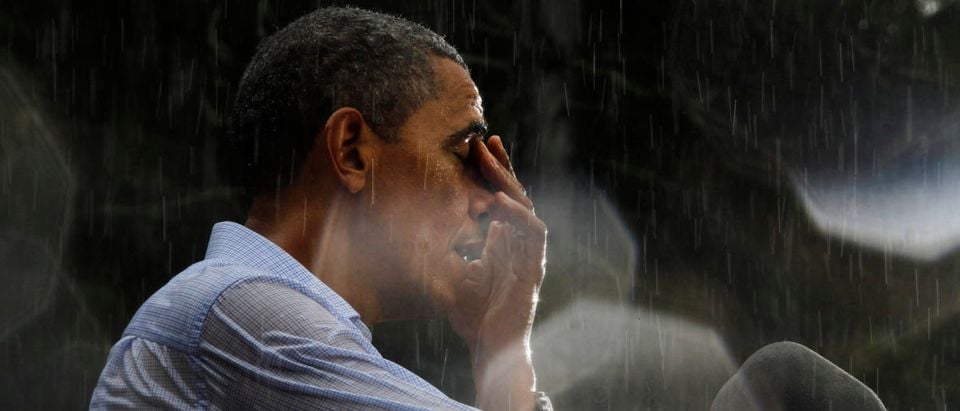 U.S. President Barack Obama wipes water off his face during a rain shower at a campaign rally in Glen Allen