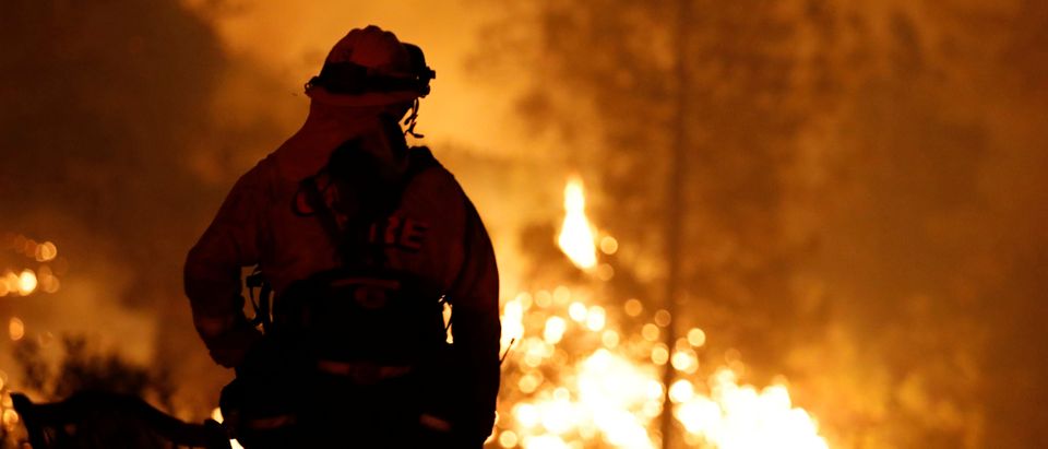 A firefighter watches the flames of the Carr Fire advance as it burns west of Redding