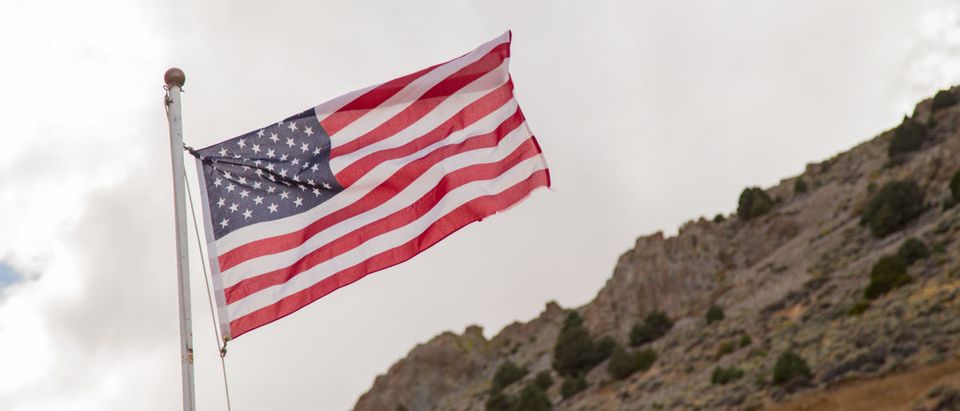 An American flag is waving in the wind around the American landscape. SHUTTERSTOCK/ Robert Guio
