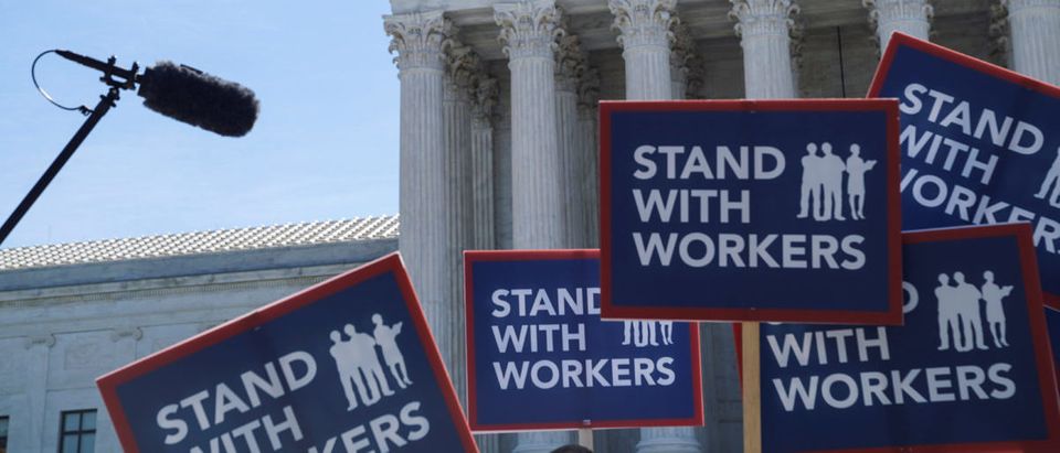 People hold signs outside the U.S. Supreme Court, waiting for the Janus v. American Federation of State, County, and Municipal Employees case in Washington