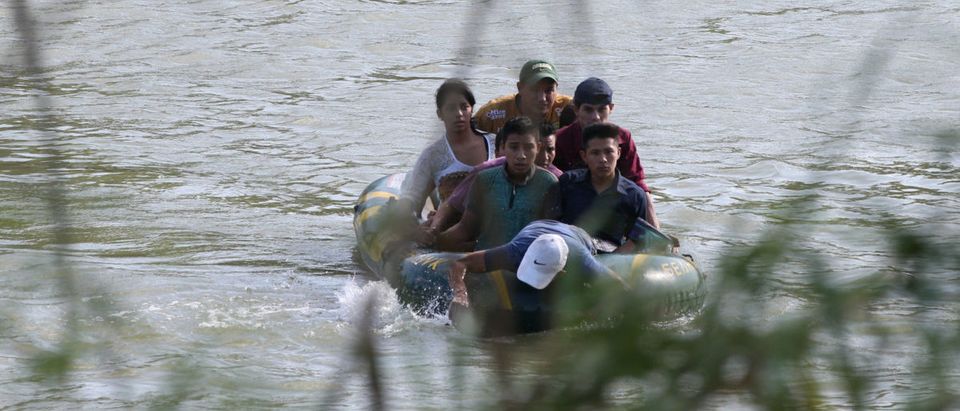 A suspected smuggler uses his arms to paddle a raft of immigrants across the Rio Grande in an illegal crossing of the Mexico-U.S. border near McAllen