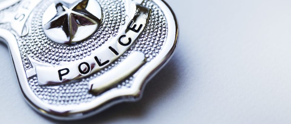 A police badge rests on a surface. Shutterstock image via user heliopix