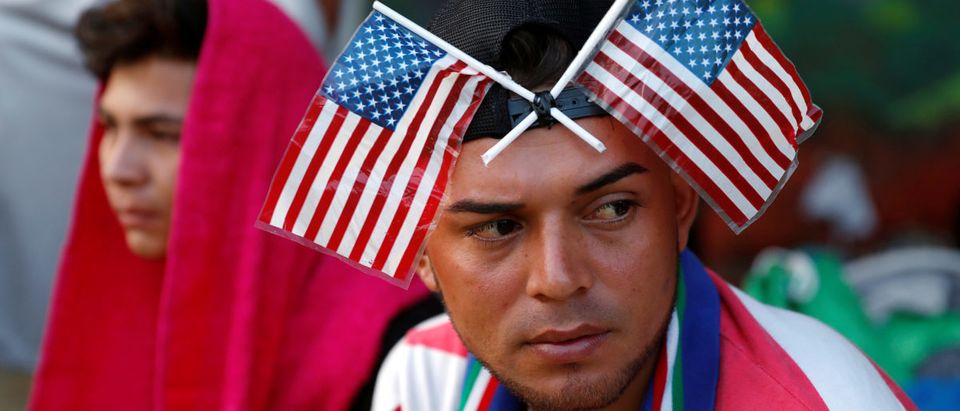 Central American migrant, part of a caravan trying to reach the U.S., is pictured with U.S. flags on his head as he waits to reunite with more migrants, in Tecun Uman