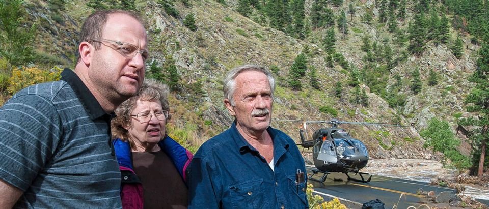 Handout photo of U.S. Representative Polis talking with two stranded people who were rescued after being spotted by a National Guard helicopter pilot along the Big Thompson River