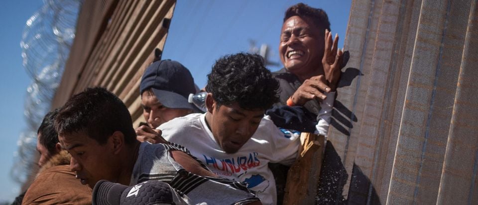 Migrants are hit by tear gas after attempting to illegally cross the border wall into the U.S. in Tijuana, Mexico