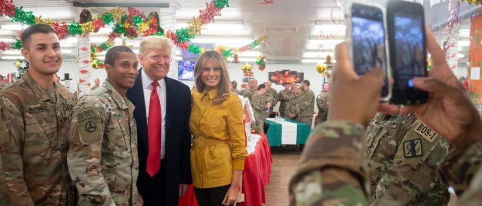 US President Donald Trump and First Lady Melania Trump take photos with members of the US military during an unannounced trip to Al Asad Air Base in Iraq on December 26, 2018. - President Donald Trump arrived in Iraq on his first visit to US troops deployed in a war zone since his election two years ago (Photo by SAUL LOEB / AFP)