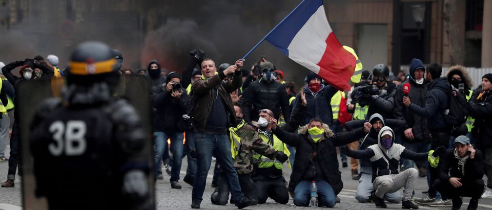 A protester waves a French flag during clashes with police at a demonstration by the "yellow vests" movement in Paris