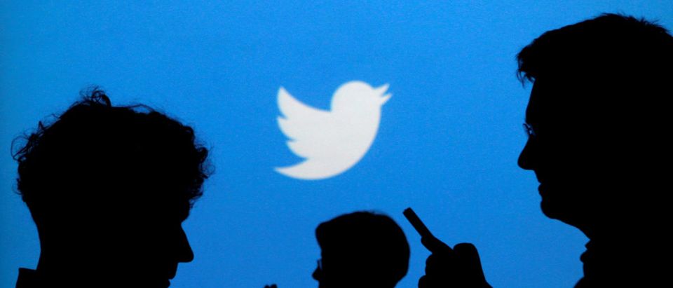People holding mobile phones are silhouetted against a backdrop projected with the Twitter logo in this illustration picture taken in Warsaw on Sept. 27, 2013. REUTERS/Kacper Pempel/File Photo