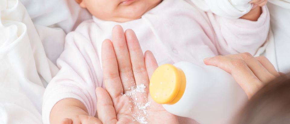A mother uses baby powder on her baby. Shutterstock image via user tomkawila