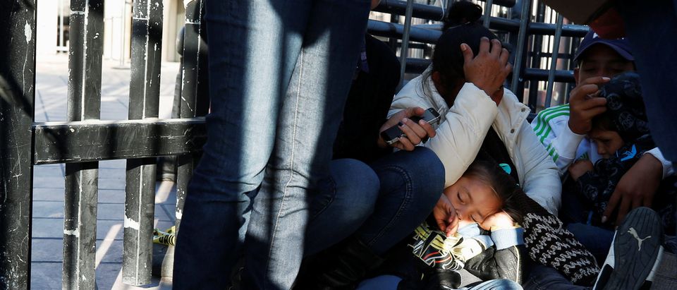 The daughter of Maria Meza, a 40-year-old migrant woman from Honduras, part of a caravan of thousands from Central America trying to reach the United States, sleeps as she waits with her mother sitting at the Otay Mesa port of entry in San Diego to be proc