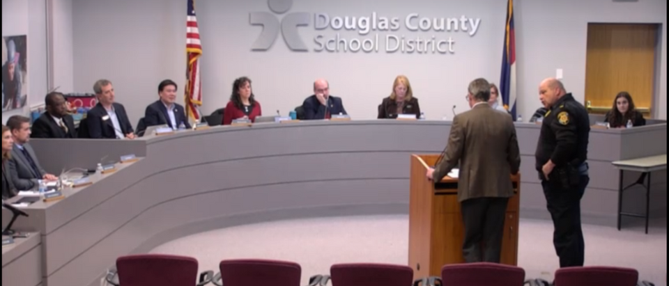 A man was escorted by a police after naming a teacher who allegedly doxxed the wrong Covington Catholic boy. Screenshot/Vimeo/Douglas County School District