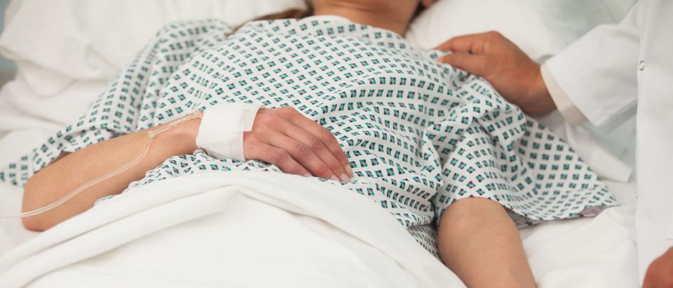 A woman lies in a hospital bed. Shutterstock image via user ESB Professional