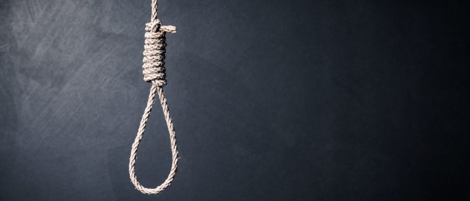 A noose hangs in a dark room. Shutterstock image via Santi S