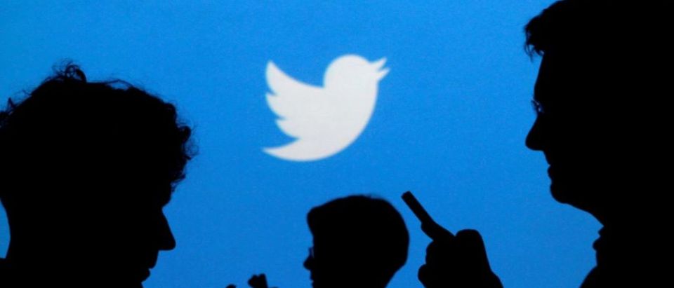 FILE PHOTO: People holding mobile phones are silhouetted against a backdrop projected with the Twitter logo in this illustration picture taken September 27, 2013. REUTERS/Kacper Pempel/Illustration/File Photo